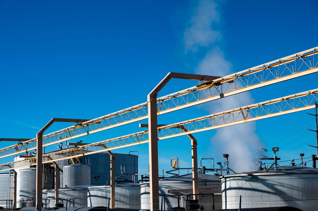 pexels-photo-1871133-1871133 Wide view of an industrial plant with smoke rising from storage tanks against a clear blue sky.